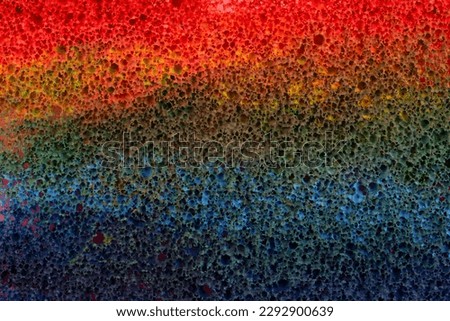 Sponge in multi-colored paint, abstract background, backdrop.