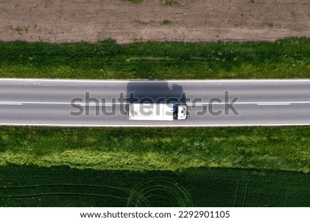 Transportation and logistics, aerial shot of truck driving along the highway through countryside on sunny summer day