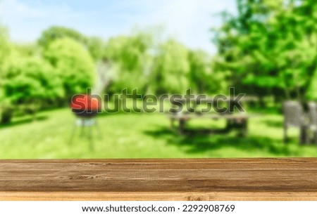 summer time in backyard garden with grill BBQ, wooden table 