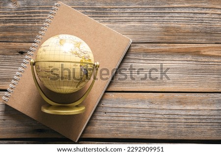 Earth globe and notebook on wooden background, top view.