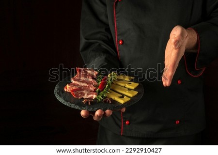 The chef presents a sliced steak with beef and cheese on a serving plate. The concept of serving dishes to order by a waiter with space for advertising on a black background.