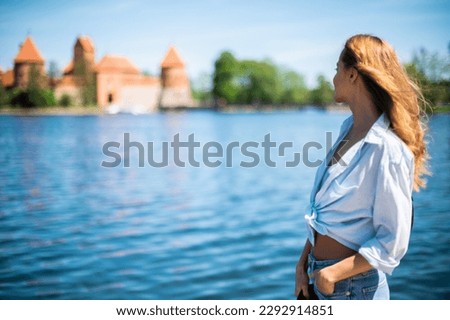 Young beautiful woman looking at the Castle of Trakai, famous landmark in Lithuania near Vilnius