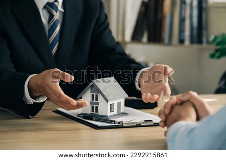 Real estate agents with house models are talking to customers about buying home and asked the customer to sign the documents to make the contract legal, Home sales and home insurance concept. 