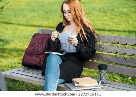 Understanding Student Loan Repayment Options. Pros and Cons of Federal vs Private Student Loans. Young student girl in glasses and with laptop and books reading letter outdoors Royalty-Free Stock Photo #2292916171