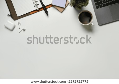 Modern white office desk table with laptop computer, cup of coffee and notebook. Top view with copy space, flat lay.