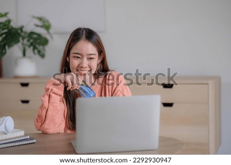 Young woman holding credit card and using laptop computer. Businesswoman working at home. Online shopping, e-commerce, internet banking, spending money, working from home concept