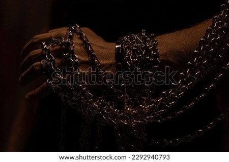 Male hand holding chains on a dark background 