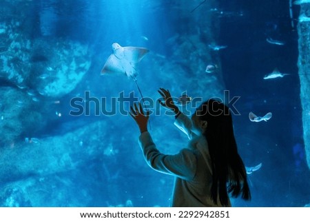 Young Asian woman enjoy and fun learning and looking sea life at Aquarium on holiday vacation. Attractive girl looking shoal of fish and aquatic animals in large glass tank during travel in Oceanarium Royalty-Free Stock Photo #2292942851