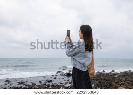 Woman take photo on cellphone over the sea