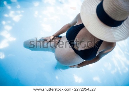 pregnant girl in bikini and hat in swimming pool