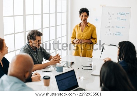 Professional black woman having a discussion with her colleagues in an office. Business woman leading a team meeting in a boardroom. Female project manager giving a presentation.