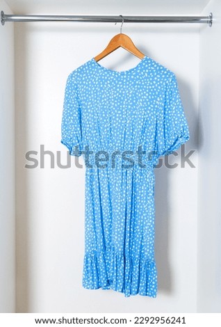 Vertical stock photo of one blue dress hanging in white closet.