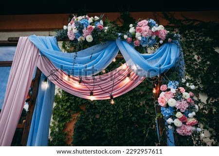 Wedding arch in pink and blue colors with fresh flowers. Creative image for your design or illustrations.