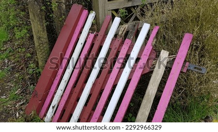 old broken fence painted pink and white lying on the ground