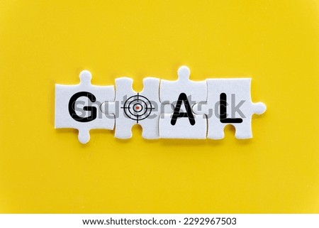GOAL text with dartboard icon on white puzzle or jigsaw over yellow background use for business,goal and achievement,success concept.