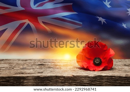 Poppy pin for Anzac Day. Poppy flower on old beautiful high grain, detailed wood on background of sunset sky and transparent Australia flag. Anzac Day Lest We Forget. Royalty-Free Stock Photo #2292968741