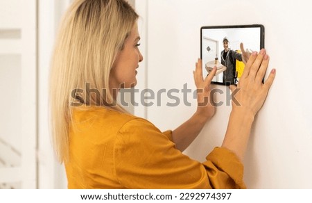 Security camera system on tablet app - Delivery man holding package in front of door cam - AI Cctv smart technology lifestyle concept Royalty-Free Stock Photo #2292974397
