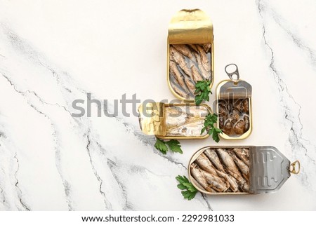 Opened tin cans with different fish and mussels on white marble table