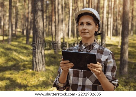 female forester or forest engineer working in the woods with digital tablet. forestry, forest management and development. copy space Royalty-Free Stock Photo #2292982635