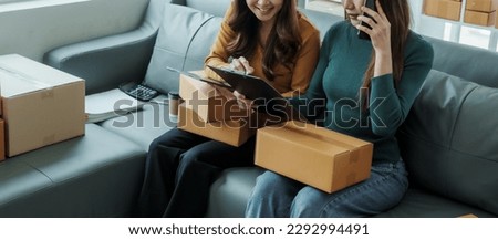 Checking clients address, Young pretty Asian female influencer small businesses SME owners female entrepreneurs working on receipt box and check online orders, sitting on sofa of home online business