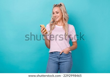 Photo of smiling satisfied blogger youth girl blonde curly hair reading phone options interface updates isolated on aquamarine color background