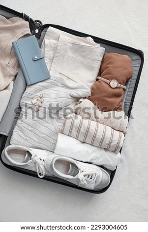 Suitcase with female clothes and accessories on white blanket Royalty-Free Stock Photo #2293004605