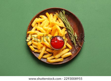 Plate with tasty french fries, rosemary and ketchup on green background Royalty-Free Stock Photo #2293008955