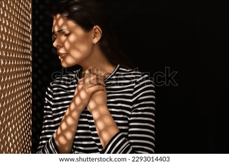 Upset woman listening to priest during confession near wooden partition in booth, space for text Royalty-Free Stock Photo #2293014403