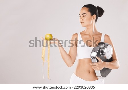 Fitness, health and woman with scale and apple for weightloss, diet and nutrition on white studio background. Exercise, wellness and girl with fruit, balance and measuring tape for healthy lifestyle