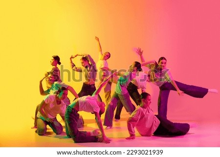 Choreography figures. School girls wearing white clothes dancing together on gradient background in neon light. Modern freestyle dance, contemporary art, movements, hobby, creative lifestyle concept Royalty-Free Stock Photo #2293021939