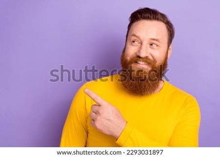 Portrait picture of young smiling guy wear yellow pullover direct finger looking empty space good news isolated on violet color background