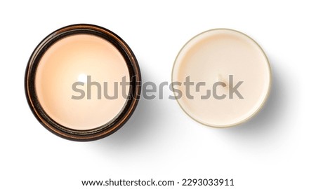 two isolated candles: burning soy way candle in an amber glass jar and a cream colored tea light, decorative lifestyle design elements over a white  background, top view, flat lay	 Royalty-Free Stock Photo #2293033911