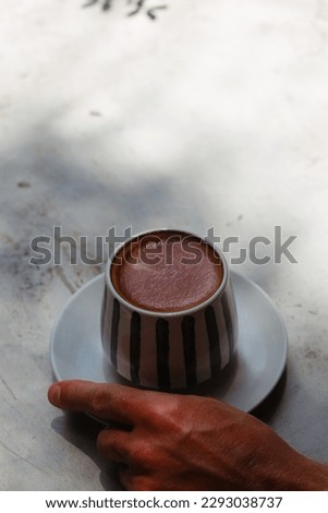 A man's hand holds a mug of coffee on a gray background in the rays of the sun. Creative concept of coffee advertising with space for text