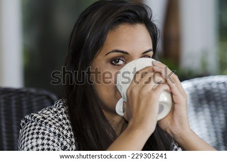 Young Indian woman raising a cup to drink