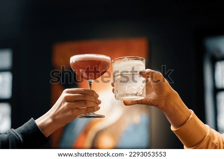 Close up of two people cheering cocktails in bar or disco club drinks and cocktails concept Royalty-Free Stock Photo #2293053553
