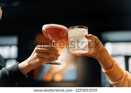 Close up of two people cheering cocktails in bar or disco club drinks and cocktails concept Royalty-Free Stock Photo #2293053559