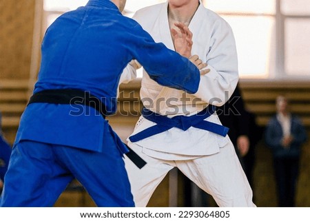 two judoists in blue and white kimono stand compete against each other, judo fight championship