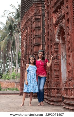A pretty Indian woman and child near a terracotta temple of West Bengal