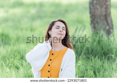 Portrait of beautiful young dark-haired woman near flowering tree. Happy model in the garden.
