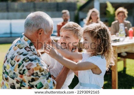 Little children having fun with their grandfather at outdoor family party. Royalty-Free Stock Photo #2293092165