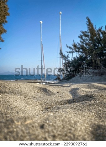 Low angle view concept picture of sand beach and sailing boat with blue ocean against blue sky