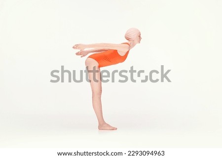 Young girl in red swimsuit and pink swimming cap standing in position to dive, training isolated over white background. Concept of retro style, sport, fashion, youth, vintage. Copy space for ad Royalty-Free Stock Photo #2293094963