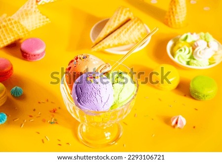 Various colorful ice cream scoops or balls sundae dish with waffle cones, macaroons on yellow background