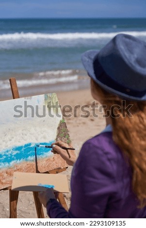 Woman painting a picture on the beach