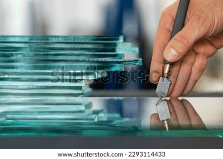 Close-up of a glazier's hand when he cuts glass in a glass factory, Close up, Pieces of thick glass Royalty-Free Stock Photo #2293114433