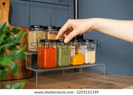 Cropped hand holding jar of spices on kitchen. Royalty-Free Stock Photo #2293121149