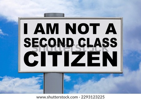 Close-up on a white billboard against a blue sky with the message "I am not a second class citizen" written in black in the middle.