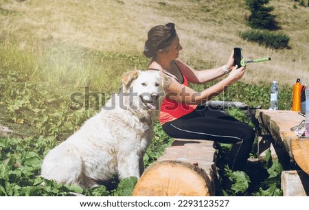 Big white  dog akbash guards a female tourist in a friendly way