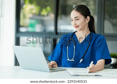 Happy positive female doctor with laptop computer and clipboard sitting at desk in modern hospital, medical at workplace, Healthcare concepts.
