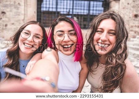 happy group of three girls looking camera and taking selfie picture with mobile phone outdoors city-Multiracial friends student having fun together on urban place- Lifestyle Concept with young female